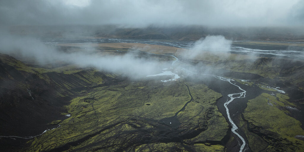 Misty landscape with river and hills.